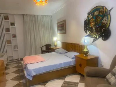 a bedroom with a bed and a chair and a lamp at Sheraton Plaza Retreat in Hurghada