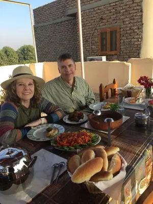 a man and woman sitting at a table with food at Pearl of Luxor on the Nile -Apartment in Luxor