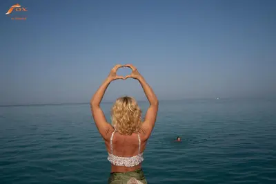 a woman in the water making a heart with her hands at Captain Beach Resort Suite in Hurghada