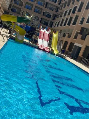 a swimming pool with a water slide in front of a building at منتجع جوليانا بيتش ريزورت in Hurghada