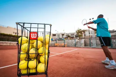 a man holding a basket of tennis balls on a tennis court at Designer Loft mit grandiosem Meerblick am roten Meer in Hurghada