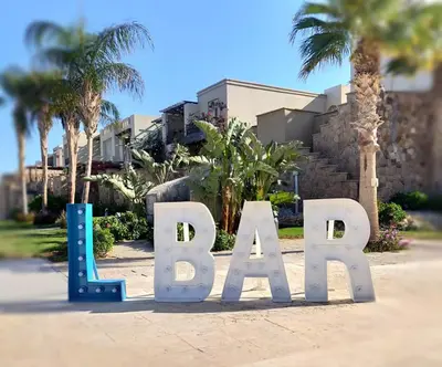 a large sign that says beach in front of palm trees at Designer Loft mit grandiosem Meerblick am roten Meer in Hurghada