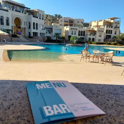 a bar sign sitting on a table next to a swimming pool at Designer Loft mit grandiosem Meerblick am roten Meer in Hurghada