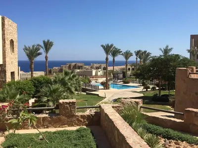 a resort with a pool and palm trees and the ocean at Designer Loft mit grandiosem Meerblick am roten Meer in Hurghada
