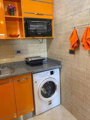 a washer and dryer in a kitchen with orange cabinets at Gravity Beach Apartment Non Egyptians only in Hurghada