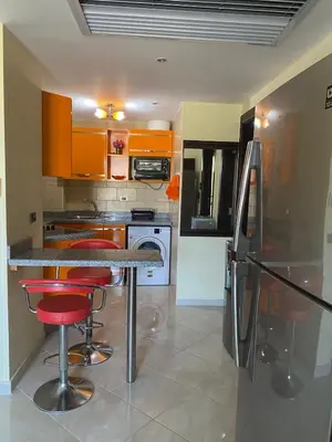 a kitchen with orange cabinets and red bar stools at Gravity Beach Apartment Non Egyptians only in Hurghada