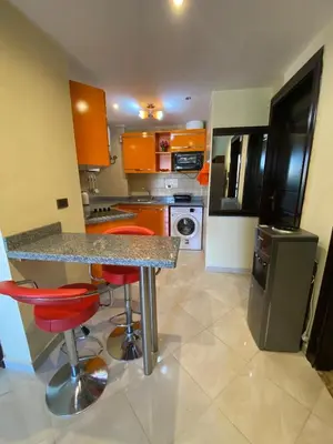 a kitchen with orange cabinets and a counter with red stools at Gravity Beach Apartment Non Egyptians only in Hurghada