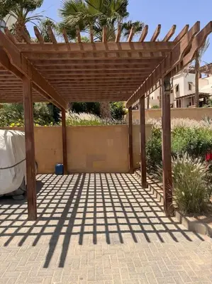 a wooden pergola sitting on a brick patio at Ancient Sands Golf Resort El Gouna Luxury Apartment in Hurghada