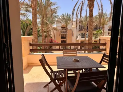 a table and chairs on a balcony with palm trees at Ancient Sands Golf Resort El Gouna Luxury Apartment in Hurghada