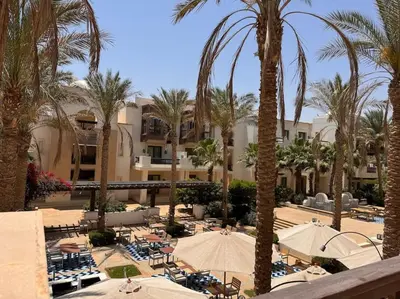 a resort with palm trees and chairs and umbrellas at Ancient Sands Golf Resort El Gouna Luxury Apartment in Hurghada