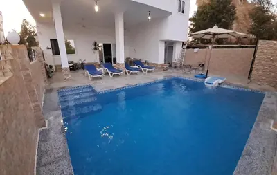 a large swimming pool with blue chairs and an umbrella at Nile Ruby Luxor in Luxor