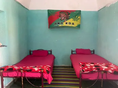 two beds in a room with a sign on the wall at Bafana Bafana Nubian Hostel in Najâ€˜ al MadÄbb
