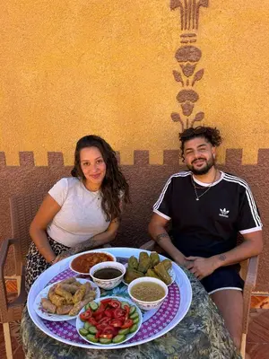 a man and woman sitting at a table with a plate of food at Bafana Bafana Nubian Hostel in Najâ€˜ al MadÄbb