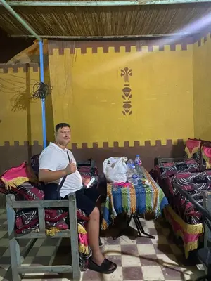 a man sitting on a bench in a room at Bafana Bafana Nubian Hostel in Najâ€˜ al MadÄbb