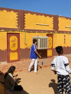 a man standing in front of a building with an ac unit at Bafana Bafana Nubian Hostel in Najâ€˜ al MadÄbb