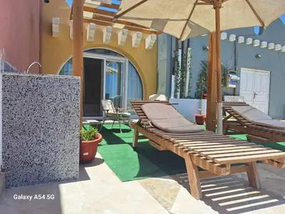 a patio with wooden benches and an umbrella at Comfort Marine in Hurghada