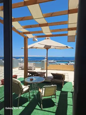 a patio with a table and an umbrella on the beach at Comfort Marine in Hurghada