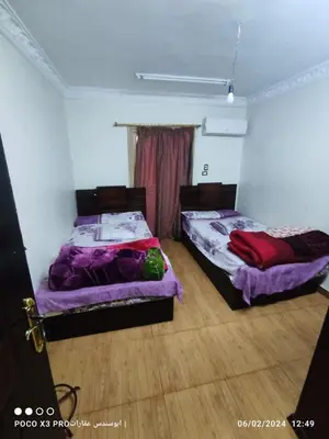two beds are in a room with wooden floors at شقة مفروشة رائعة كورنيش النيل برج الرياض in Naj‘ al ‘Amrāb