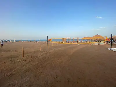 a sandy beach with umbrellas and the ocean at Mangroovy retreat in Hurghada