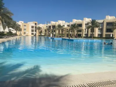 a large swimming pool with palm trees and buildings at Mangroovy retreat in Hurghada