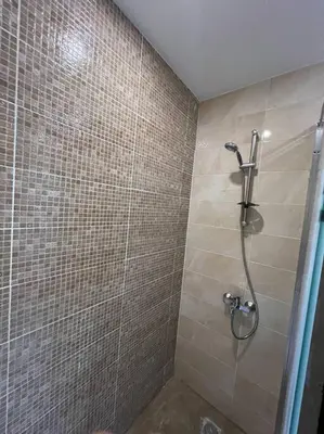 a shower in a bathroom with a tiled wall at Elegant 2-Bedroom Suite Mirage Bay in Hurghada