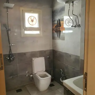 a bathroom with a toilet and a window and a sink at Lareen's apartment in Quseir