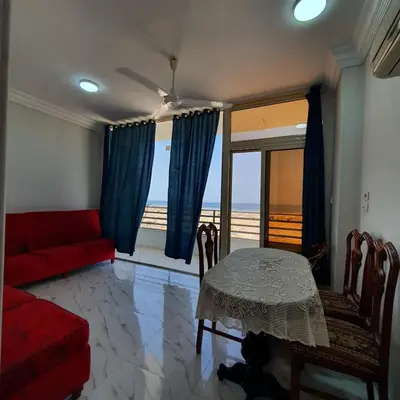 a living room with a red couch and a table at Lareen's apartment in Quseir