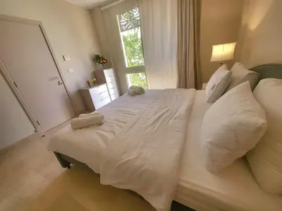 a large white bed in a bedroom with a window at Mangroovy- 1BR Sparkling Condo in Hurghada