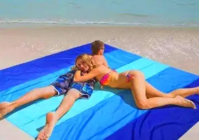 a man and a woman laying on a blue blanket on the beach at Davinci Beach Resort in Hurghada