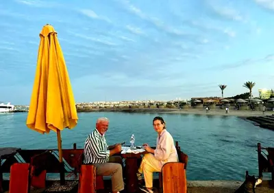 a man and woman sitting at a table next to an umbrella at Davinci Beach Resort in Hurghada