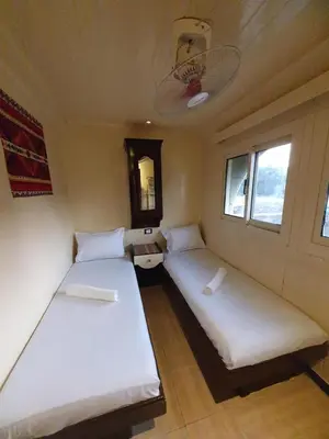 two beds in a small room with two windows at Moon Boat in Luxor