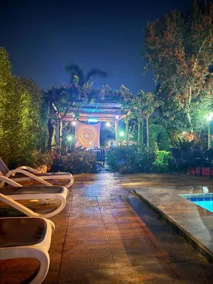 a patio with chairs and a pool at night at Villa Barba Luxor in Luxor