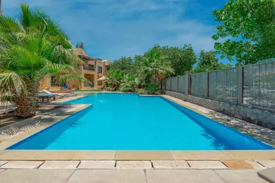 a blue swimming pool with a fence and palm trees at Beautiful apartment with terrace to the pool in Hurghada