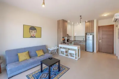 a living room with a blue couch and a kitchen at Sunny 1BR Retreat Newest Project Shedwan El Gouna Lagoon & Pool in Hurghada