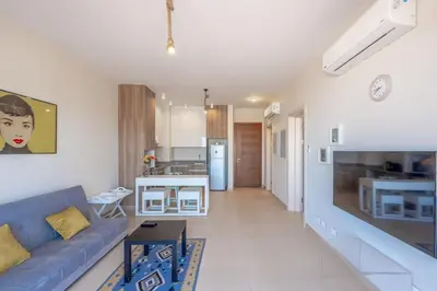 a living room with a blue couch and a kitchen at Sunny 1BR Retreat Newest Project Shedwan El Gouna Lagoon & Pool in Hurghada