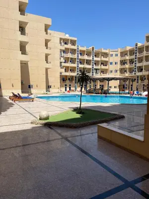 a palm tree in front of a building with a pool at Wavesong Whispers flat where you can enjoy seaview with the best price and enjoy speedy wifi in Hurghada