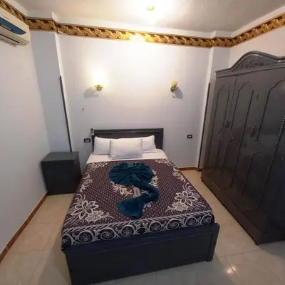 a bedroom with a bed with a blue robe on it at Pauline Guest House in Luxor