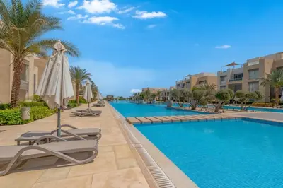 a swimming pool with lounge chairs and an umbrella at Stylish Gouna Escape 2BR Mangroovy Beach Pool Access in Hurghada