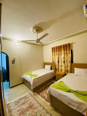 a bedroom with two beds and a ceiling fan at Basmatic2 Nubian Guest House in Aswan