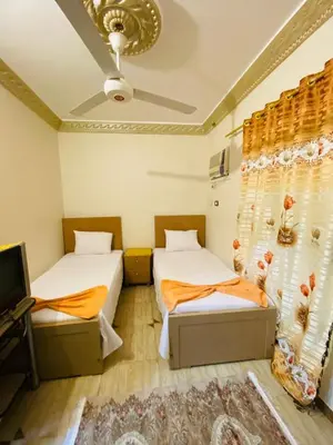 two beds in a room with a tv and curtains at Basmatic2 Nubian Guest House in Aswan