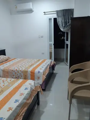 two beds in a room with a chair and a window at الغردقة الدهار القيادات in Hurghada
