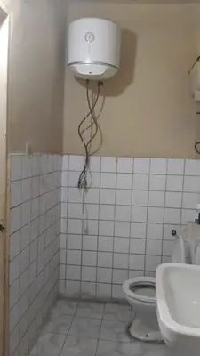 a bathroom with a toilet and a light on the wall at Pito home in Luxor