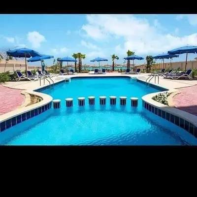 a large swimming pool with blue umbrellas and chairs at Casablanca Beach hurgada كازابلانكا بيتش الغردقه in Hurghada