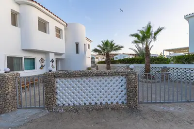 a fence in front of a house with palm trees at Aden Beach - Sea View room with beach access in Villa in Hurghada