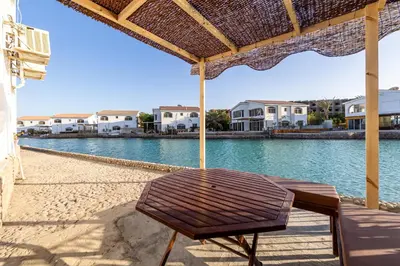 a bench sitting on the beach under an umbrella at Aden Beach - Sea View room with beach access in Villa in Hurghada