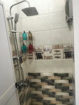 a bathroom with a shower with a tiled floor at Aswan Key Cozy in Nag` el-Ramla