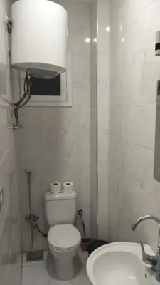 a white bathroom with a toilet and a sink at Aswan Key Cozy in Nag` el-Ramla