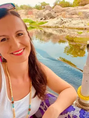 a young woman sitting next to a body of water at Felucca sailing boat from Aswan to komombo with private bathroom in Aswan