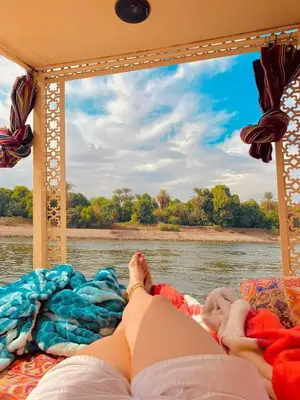 a person laying on a bed on a boat on the water at Felucca sailing boat from Aswan to komombo with private bathroom in Aswan