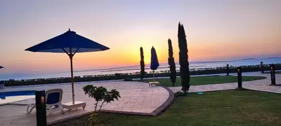 a pool with an umbrella and trees and the sunset at Susi`s TheView Luxuriöse Ferienwohnung mit fantastischem Meerblick in Hurghada